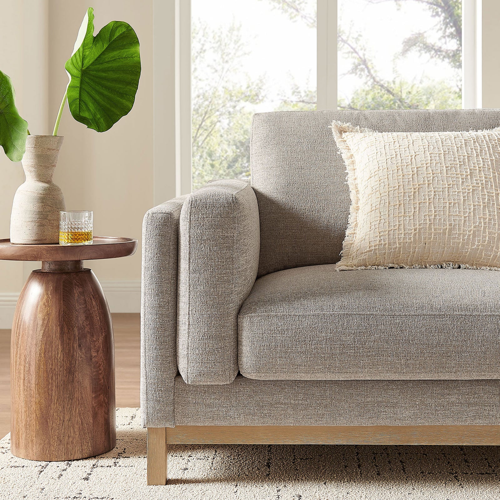 Styled corner of the Roscoe sofa in a bright living room with accent table, pillow, and greenery || EEI-7327-PEW || detail_room