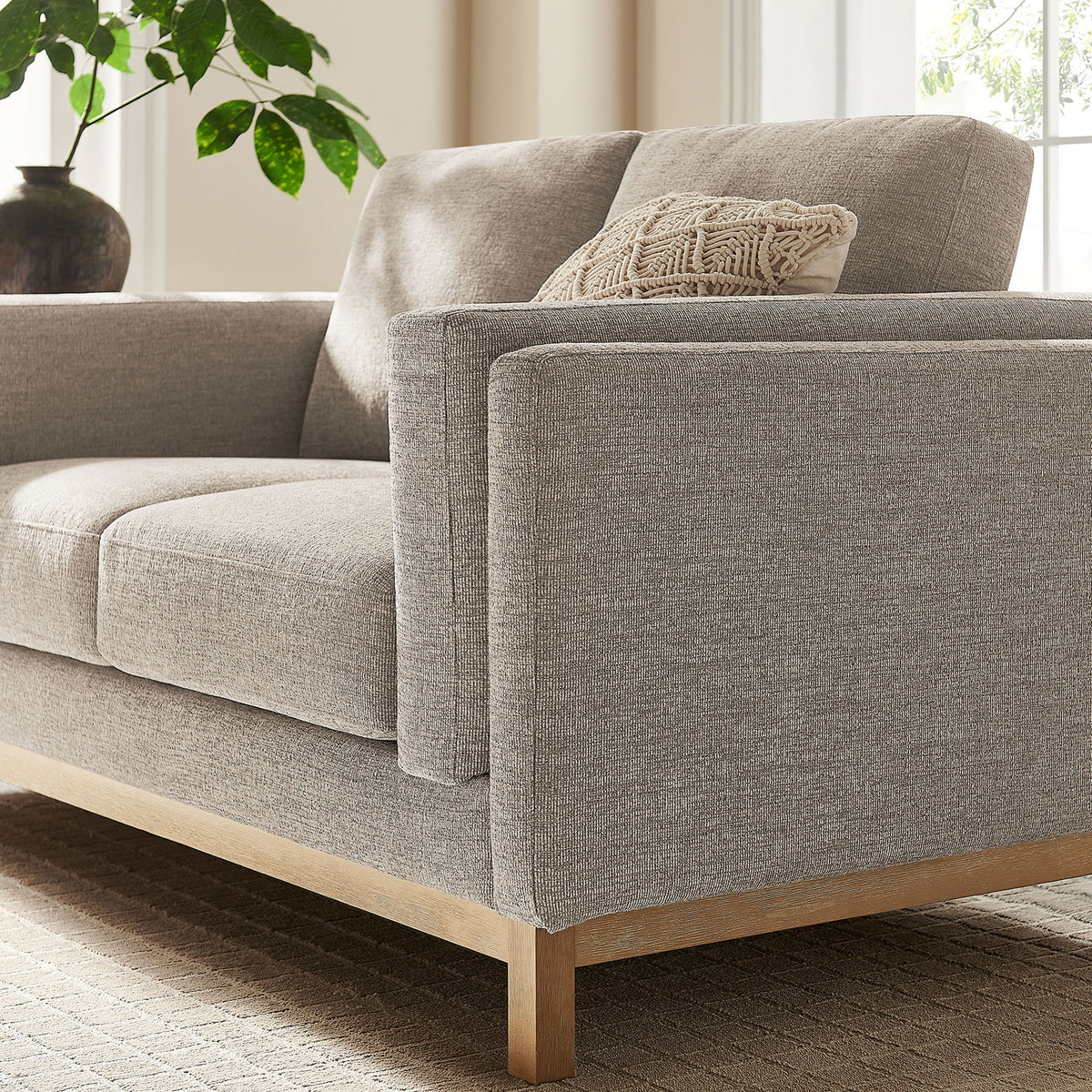 Pewter loveseat styled with a textured pillow, wood base, and soft natural light for a cozy feel. || EEI-7328-PEW || detail_room