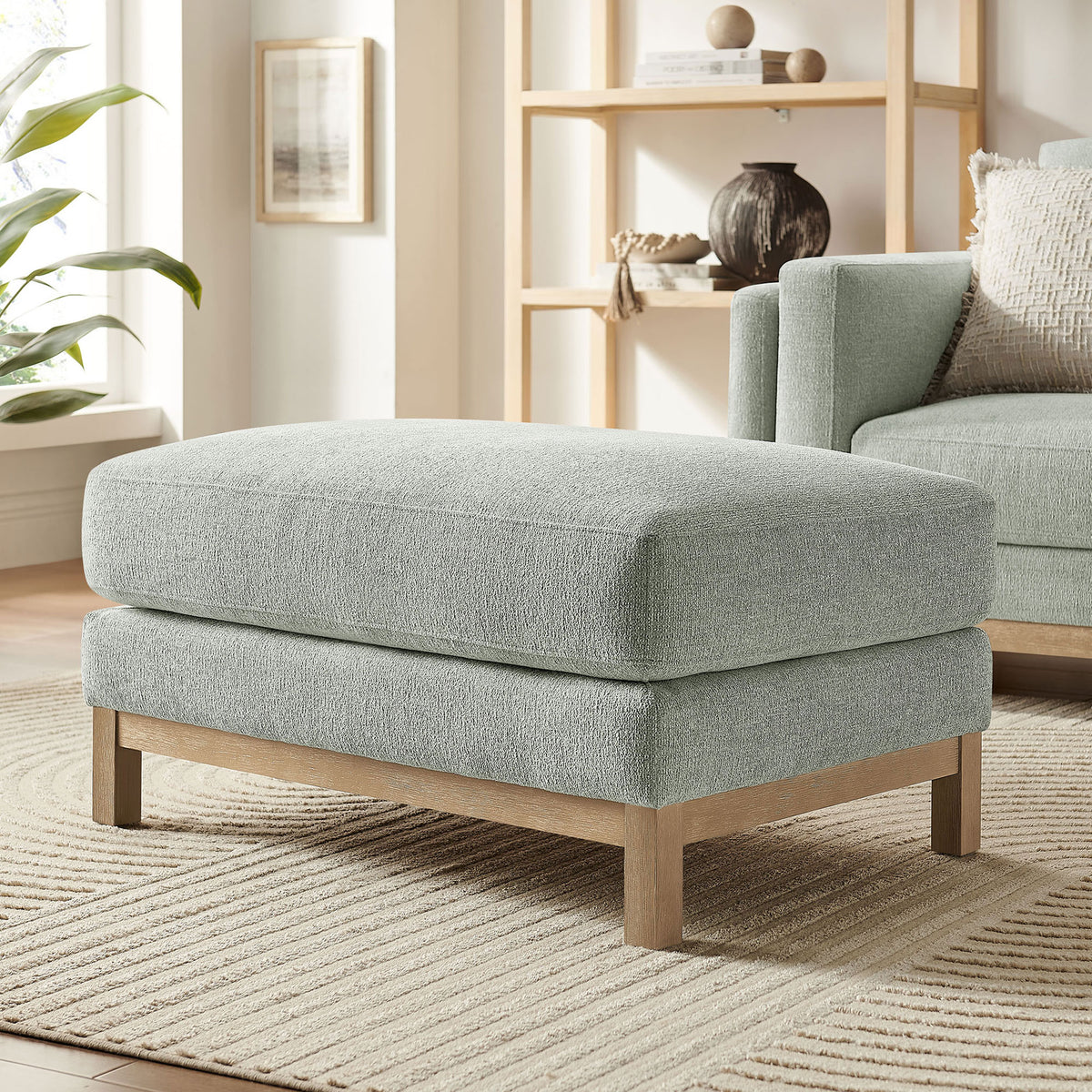 Mist ottoman styled in a bright living room with matching sofa, wood base, and textured rug || EEI-7330-MST || front_angle_room