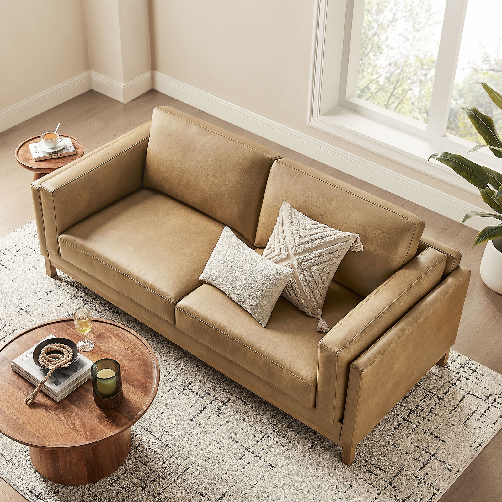 Roscoe sofa revealing wide seating, plush back cushions, and warm toast vegan leather finish in a sunlit room || EEI-7335-TST || top_angle_room