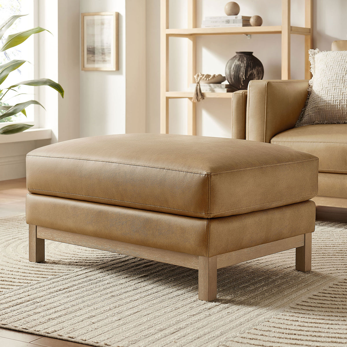 Roscoe toast vegan leather ottoman styled in a bright living room with neutral rug and decor || EEI-7338-TST || front_angle_room
