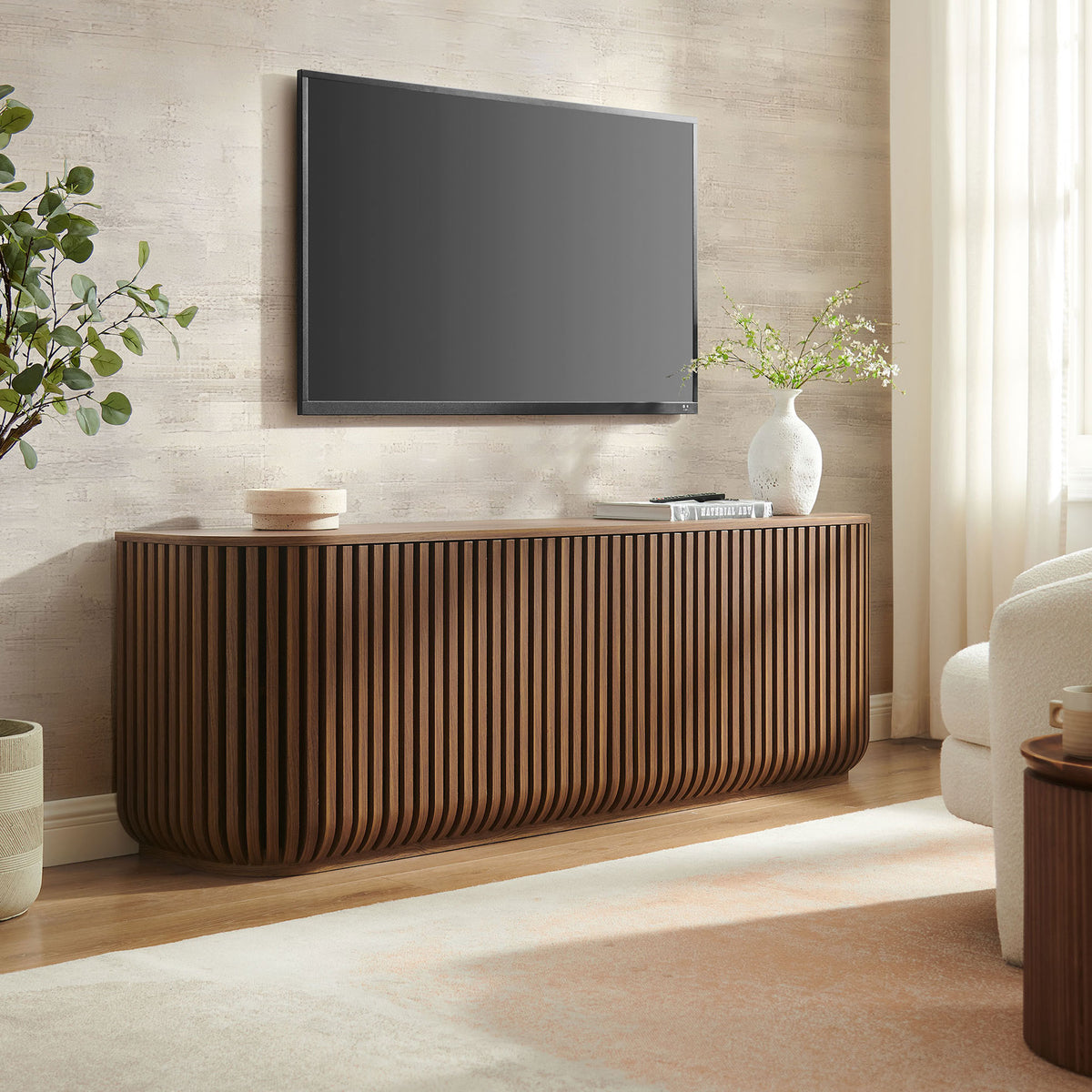 Walnut fluted sideboard styled as a media console beneath a wall-mounted TV in a modern living room || EEI-7359-WAL || front_angle_room