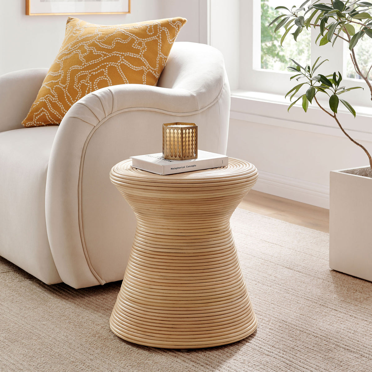 Natural rattan hourglass side table beside a plush sofa, adding organic warmth to a bright modern living room || EEI-7360-NAT || front_angle_room