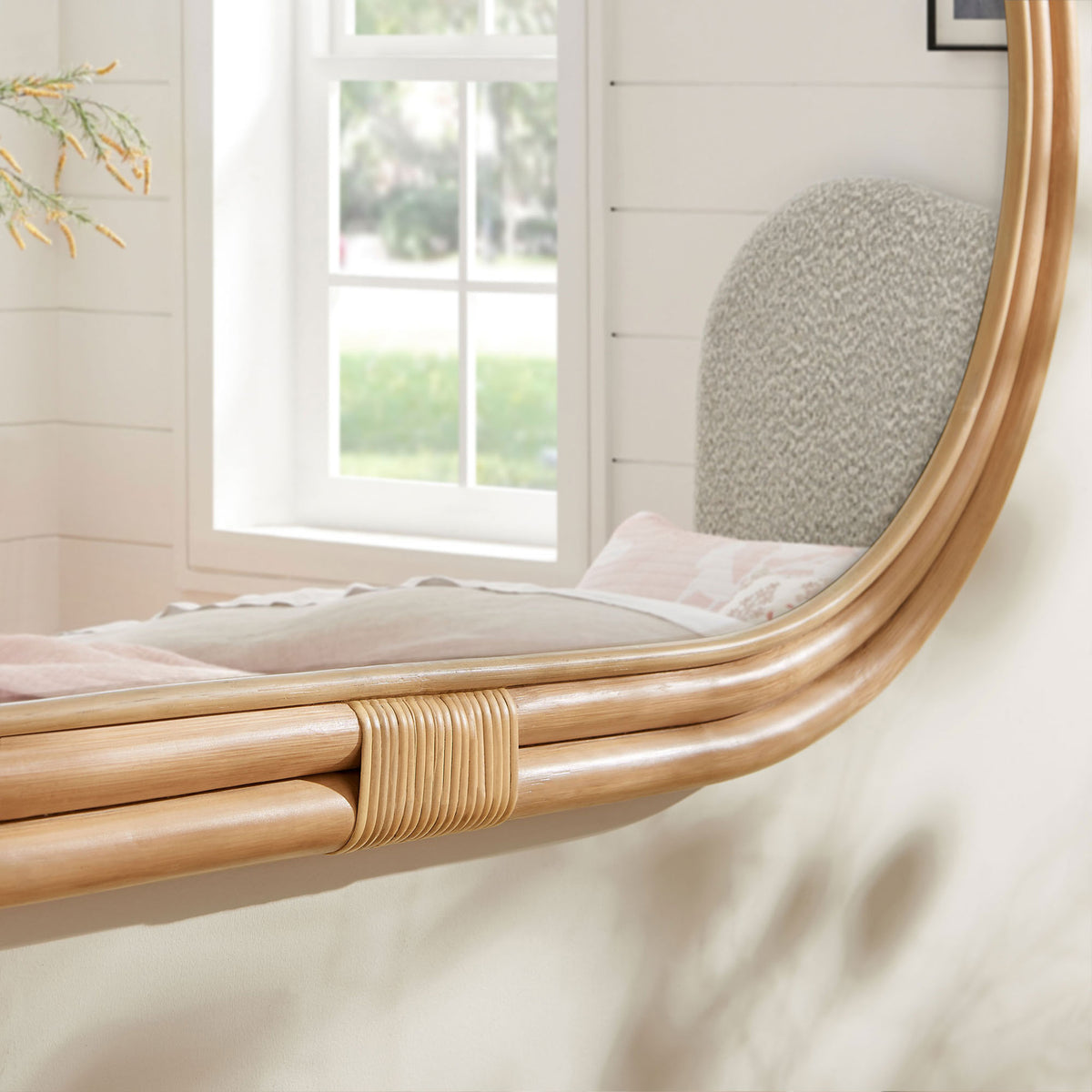 Corsica oval rattan mirror edge adding warm texture beside a window and upholstered bed || EEI-7364-NAT || detail_room