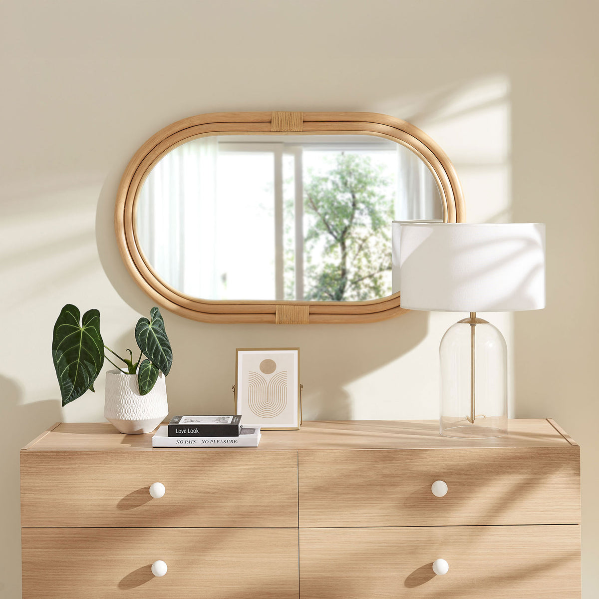 Corsica oval rattan wall mirror styled above a light wood dresser in a breezy bedroom || EEI-7364-NAT || front_room