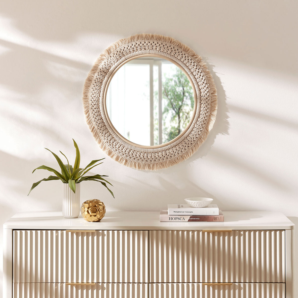 Round rattan macrame wall mirror styled above a modern dresser, adding airy boho character to the room. || EEI-7367-NAT || front_room