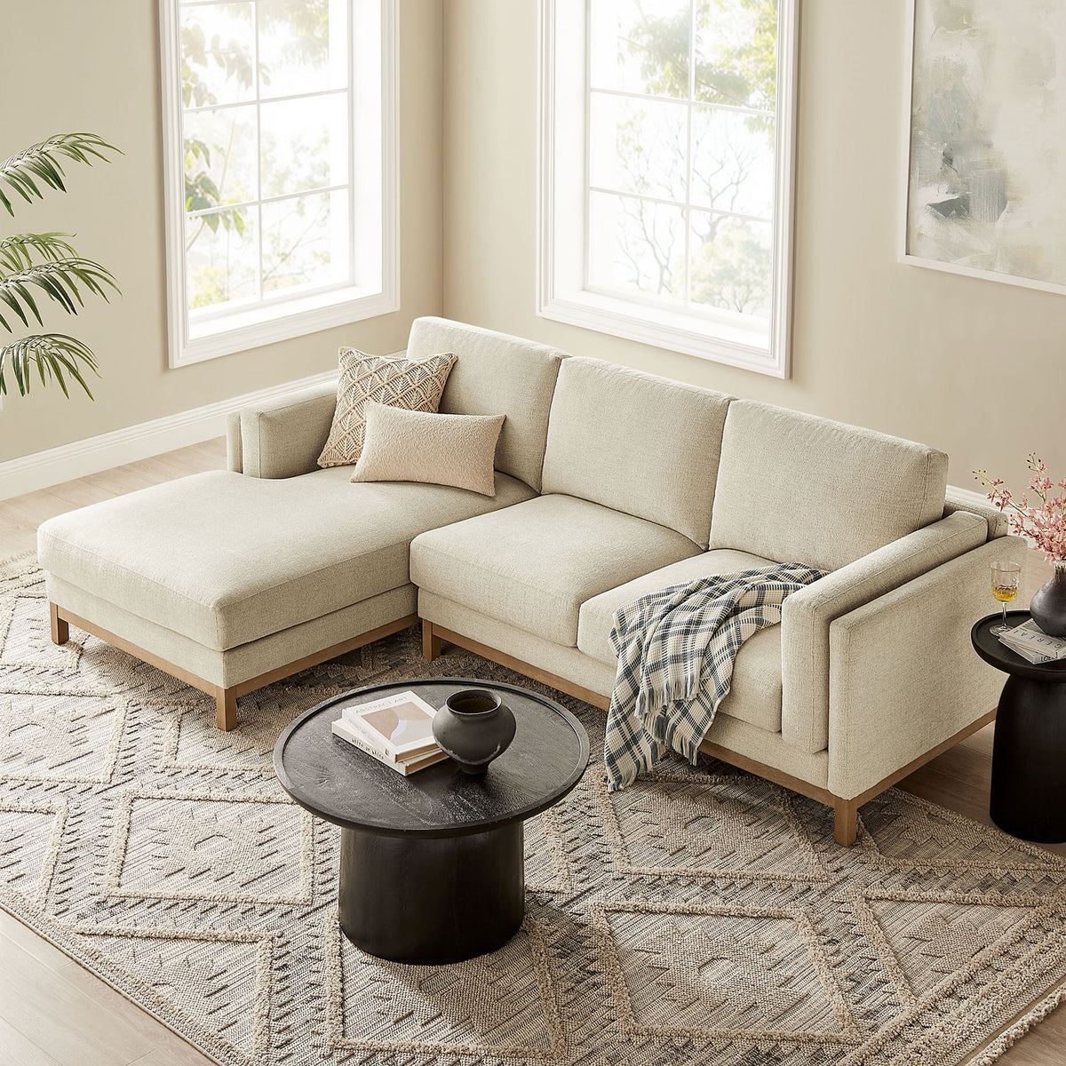 Ivory sectional sofa with left chaise layered over a patterned rug, accented by soft neutral pillows and black table || EEI-7374-IVO || front_angle_room