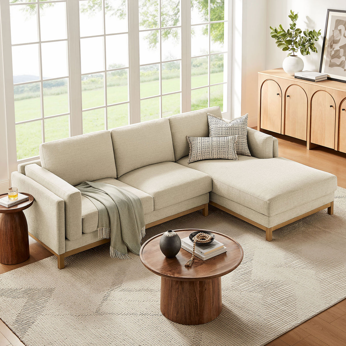Right-facing ivory sectional with chaise dressed in soft throws and pillows before expansive windows and warm storage || EEI-7375-IVO || front_angle_room