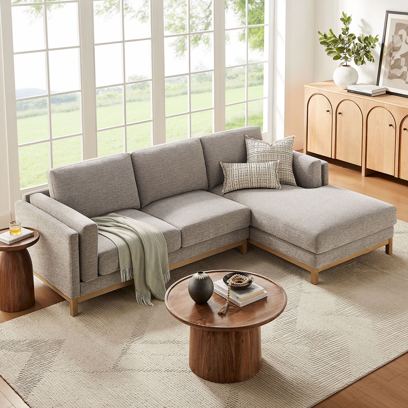 Right-facing pewter sectional anchored on a light rug with accent pillows, throw blanket, and round tables. || EEI-7375-PEW || front_angle_room