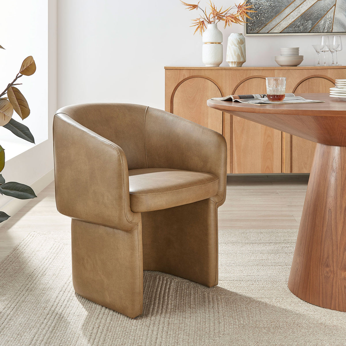Toast vegan leather barrel dining chair styled at a modern wood table in a bright dining room. || EEI-7383-TST || front_angle_room