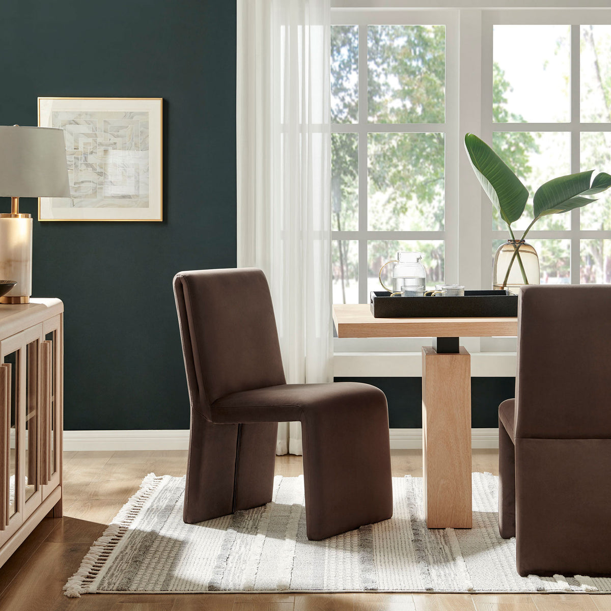 Emory chocolate velvet dining chairs surrounding a light wood table in an airy, sunlit dining room. || EEI-7384-CHB || front_angle_room