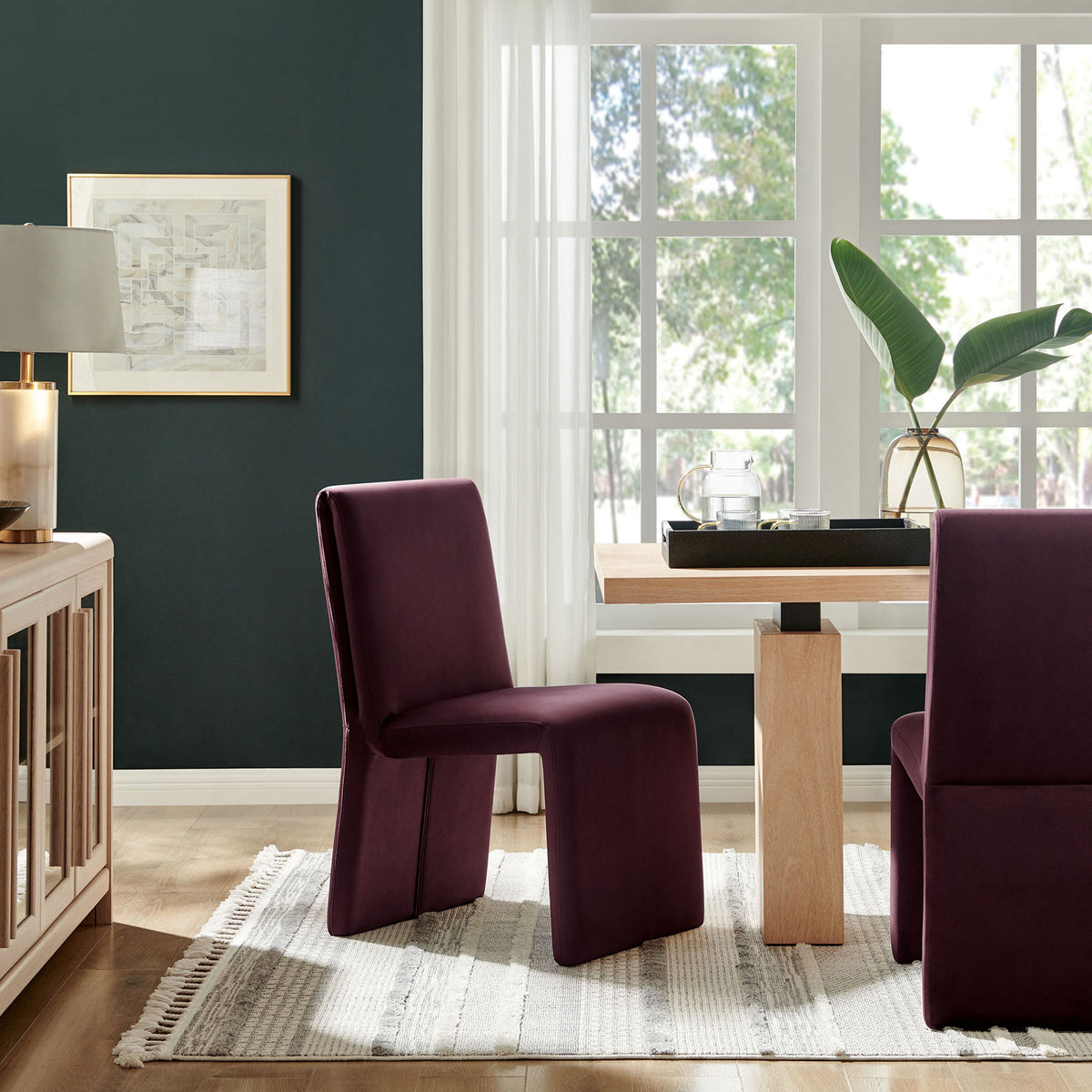 Pair of mulberry velvet dining chairs around a modern wood table in a bright windowed dining room || EEI-7384-MUL || front_angle_room