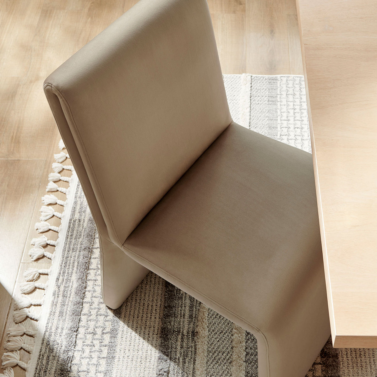 Taupe Emory dining chair tucked at a light wood table, bringing soft texture to a modern neutral dining space || EEI-7384-TAU || front_angle_room
