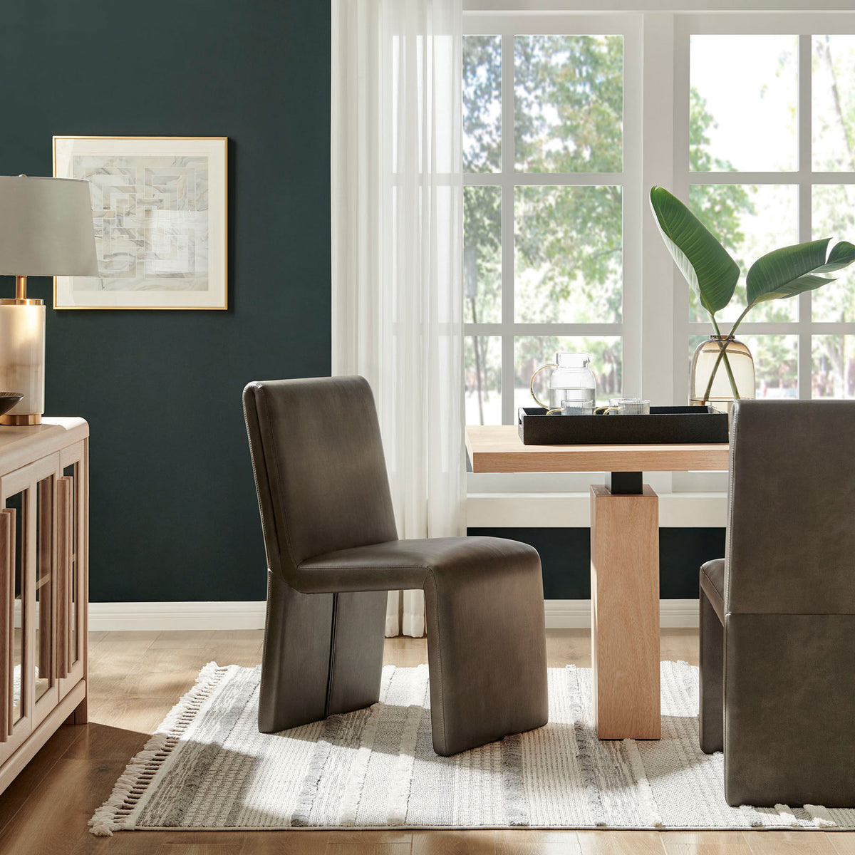 Emory dining chairs styled in a bright modern dining room with wood table, rug, and airy window backdrop || EEI-7385-MUS || front_angle_room
