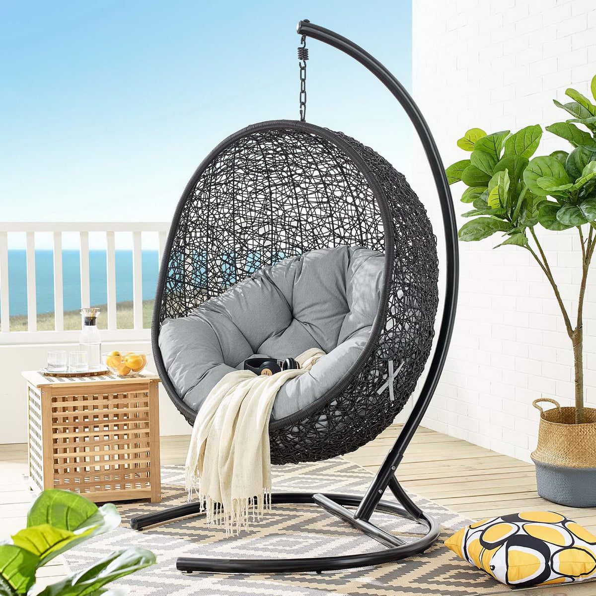 Gray cushioned egg chair with stand anchors a modern coastal balcony lounge || EEI-739-GRY-SET || front_angle_room
