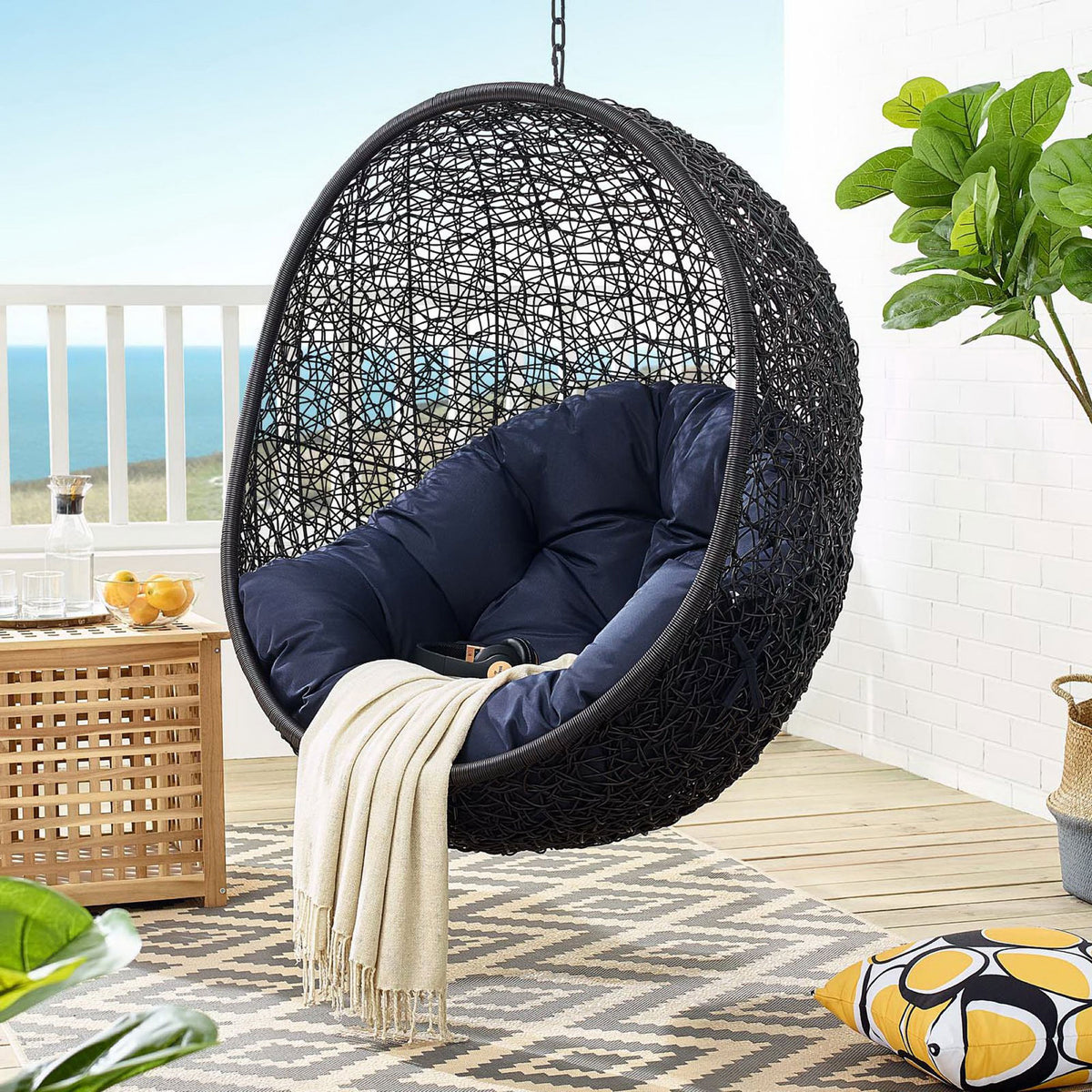 Navy cushion swing chair hangs on a breezy balcony, paired with throw and coastal decor || EEI-739-NAV-SET || front_partial_room