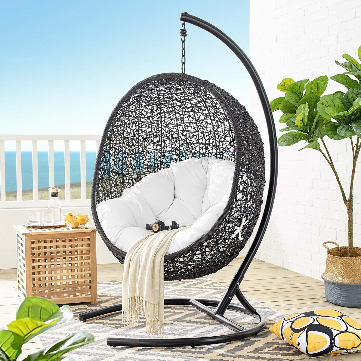 White cushioned egg chair with stand becomes the centerpiece of a bright oceanview patio