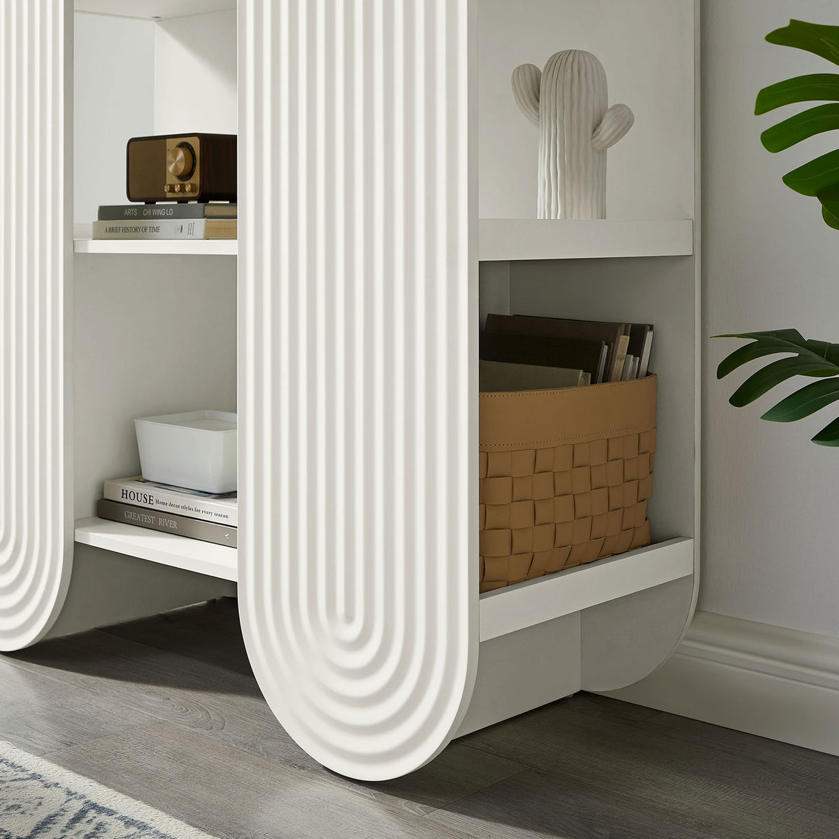 Styled lower shelf displays books and baskets within the sculptural arched frame || EEI-7390-WHI || detail_room