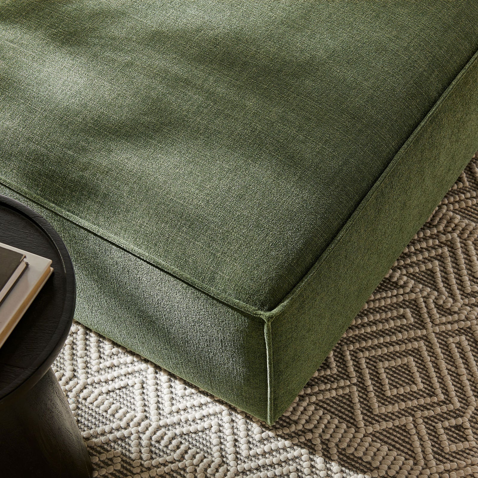 Foliage green ottoman corner styled on a textured rug beside a black side table for modern warmth || EEI-7401-FOL || detail_room