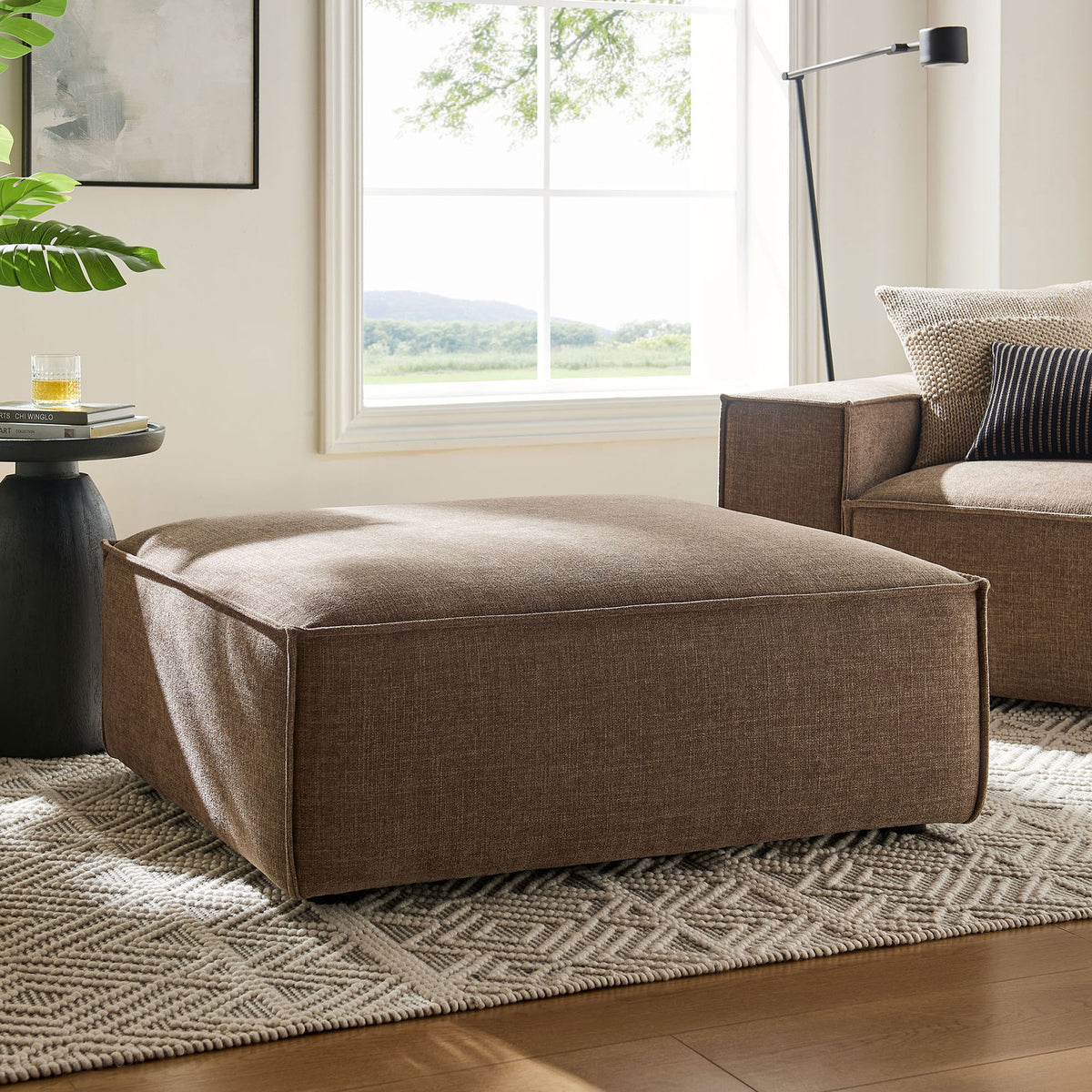 Modern mocha ottoman anchors a bright living room, offering generous cushioned comfort in performance fabric || EEI-7401-MOC || front_angle_room