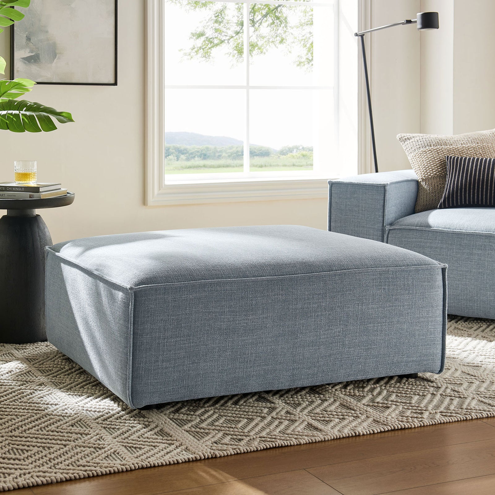 Modular sky blue ottoman anchors a bright living room, offering flexible seating beside a matching sofa and side table || EEI-7401-SKY || front_angle_room
