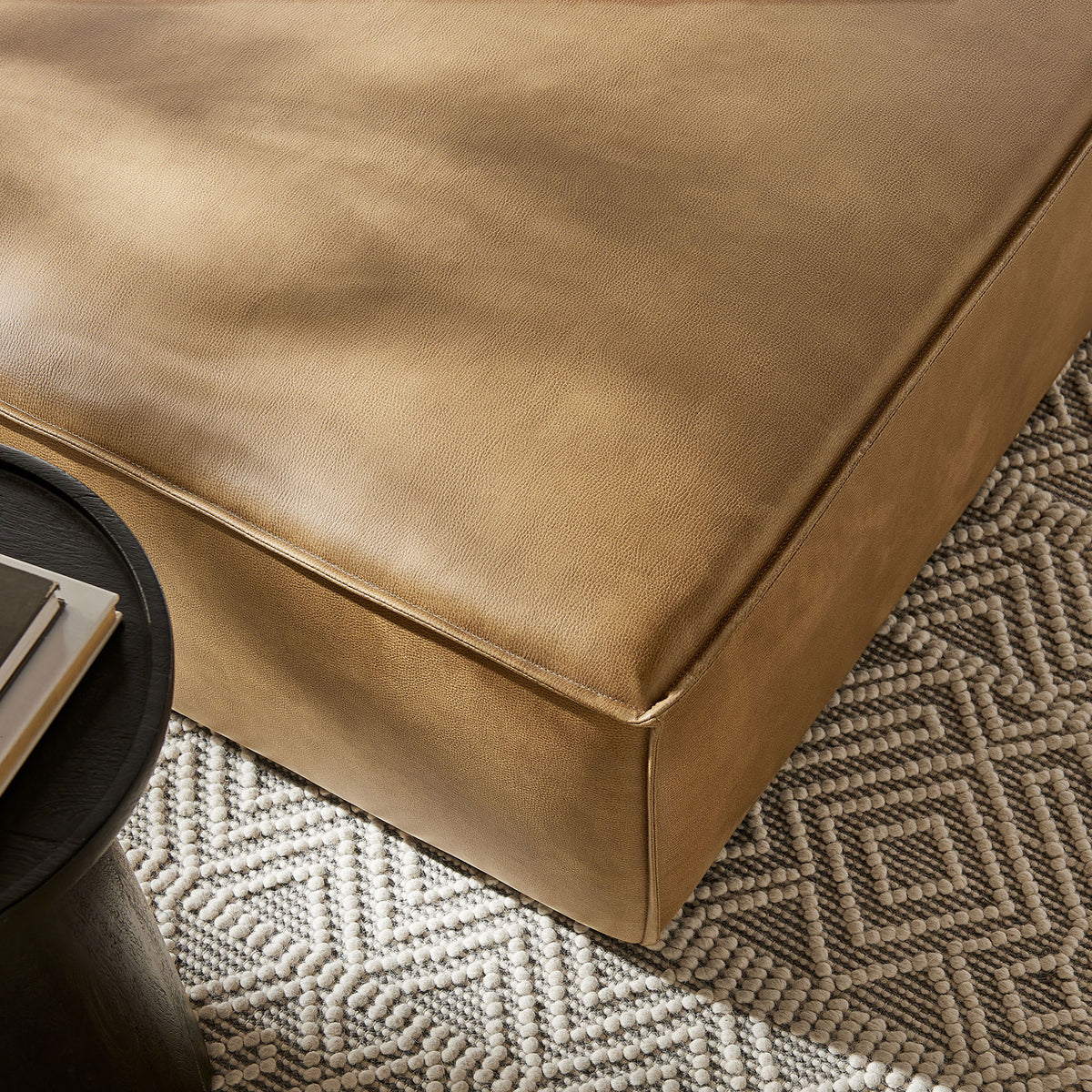 Textured vegan leather ottoman pairs with patterned rug for a warm, inviting living room look || EEI-7402-TST || detail_room