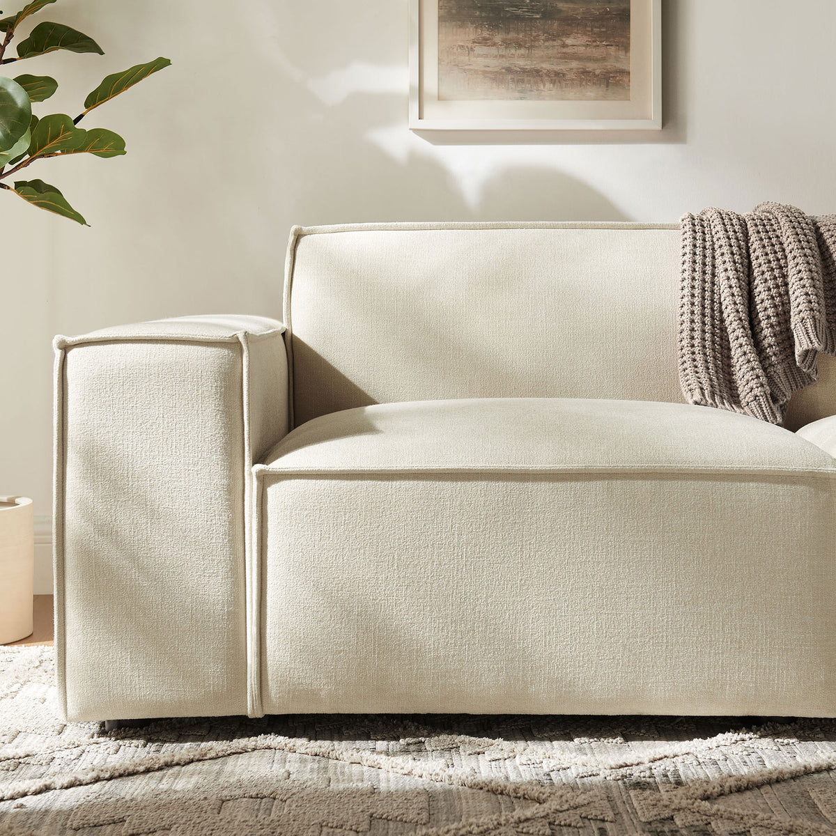Soft ecru upholstery with French piping and wide armrest, layered with a textured knit throw for added warmth. || EEI-7403-ECR || detail_room