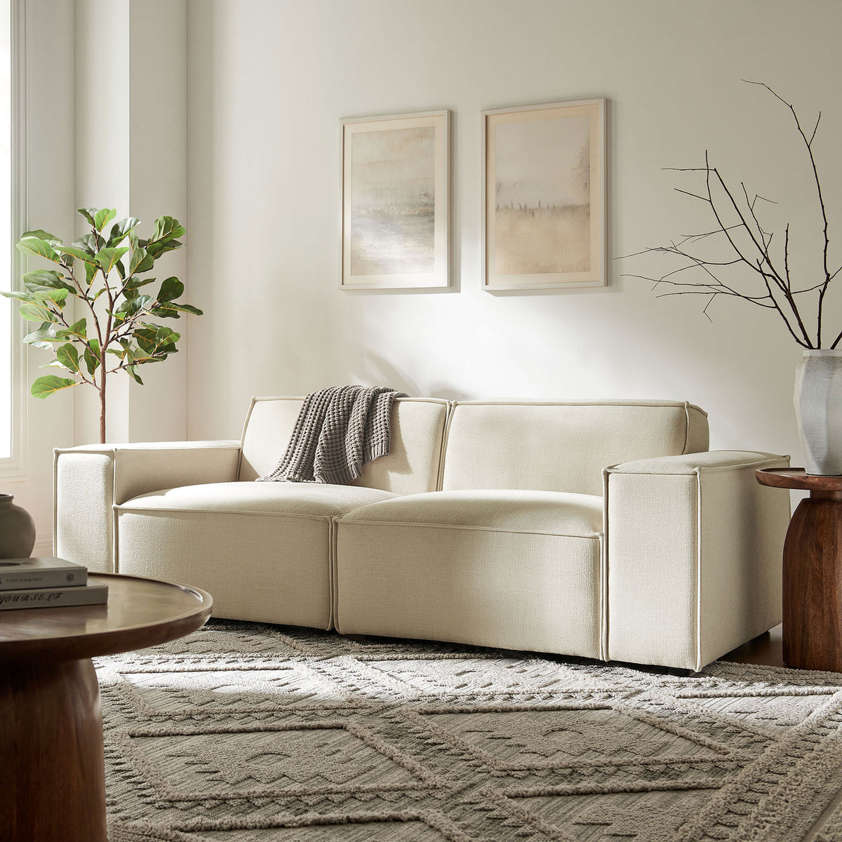 Ecru modular loveseat styled in a bright living room with textured rug, artwork, and cozy throw blanket. || EEI-7403-ECR || front_room