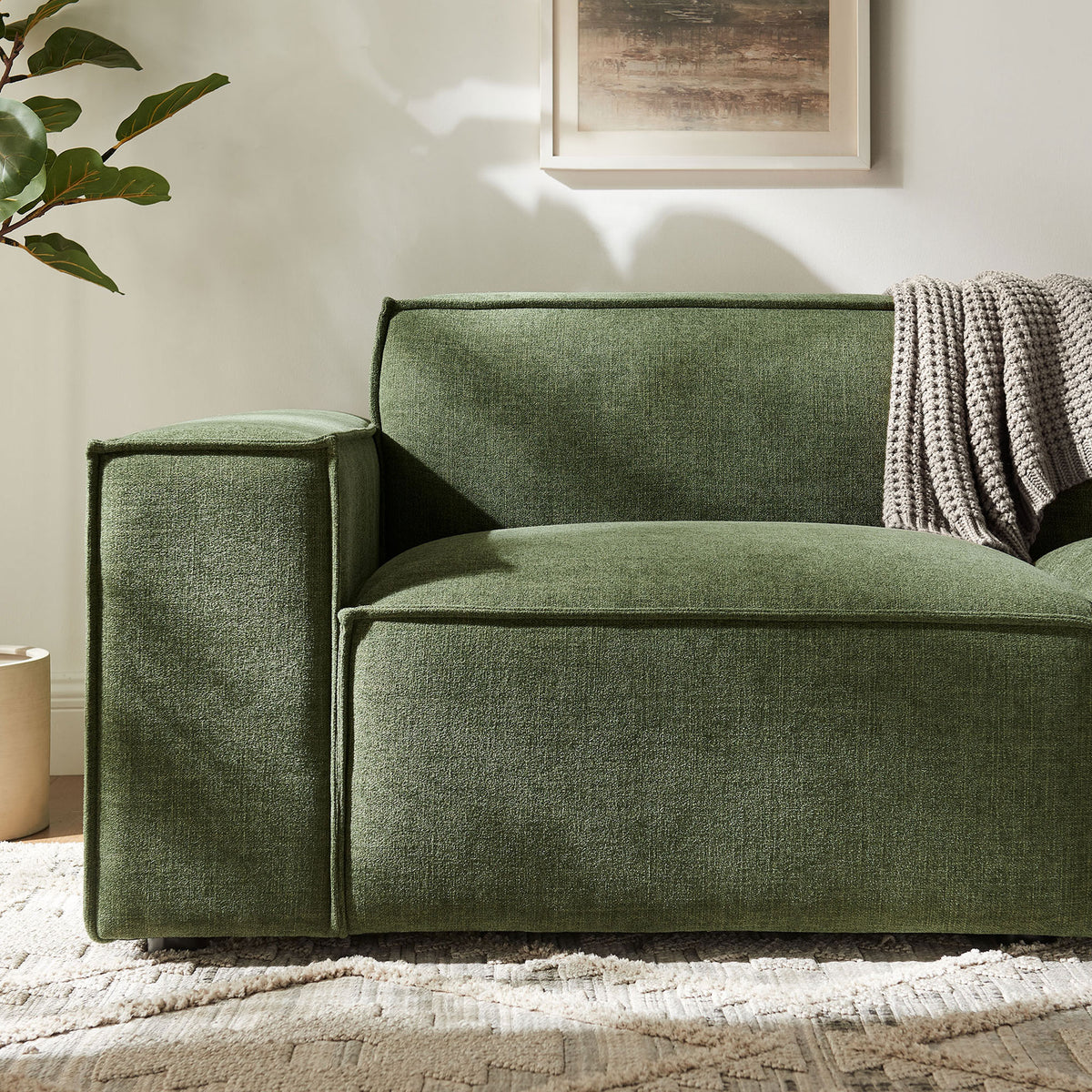 Foliage green loveseat arm with textured performance fabric, cozy knit throw, and soft patterned rug. || EEI-7403-FOL || detail_room