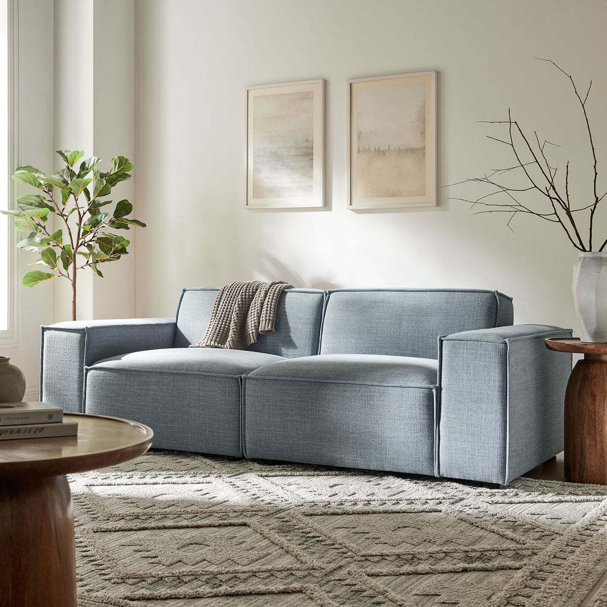 Low-profile sky blue loveseat with wide arms styled beside wood accent tables and greenery || EEI-7403-SKY || front_angle_room