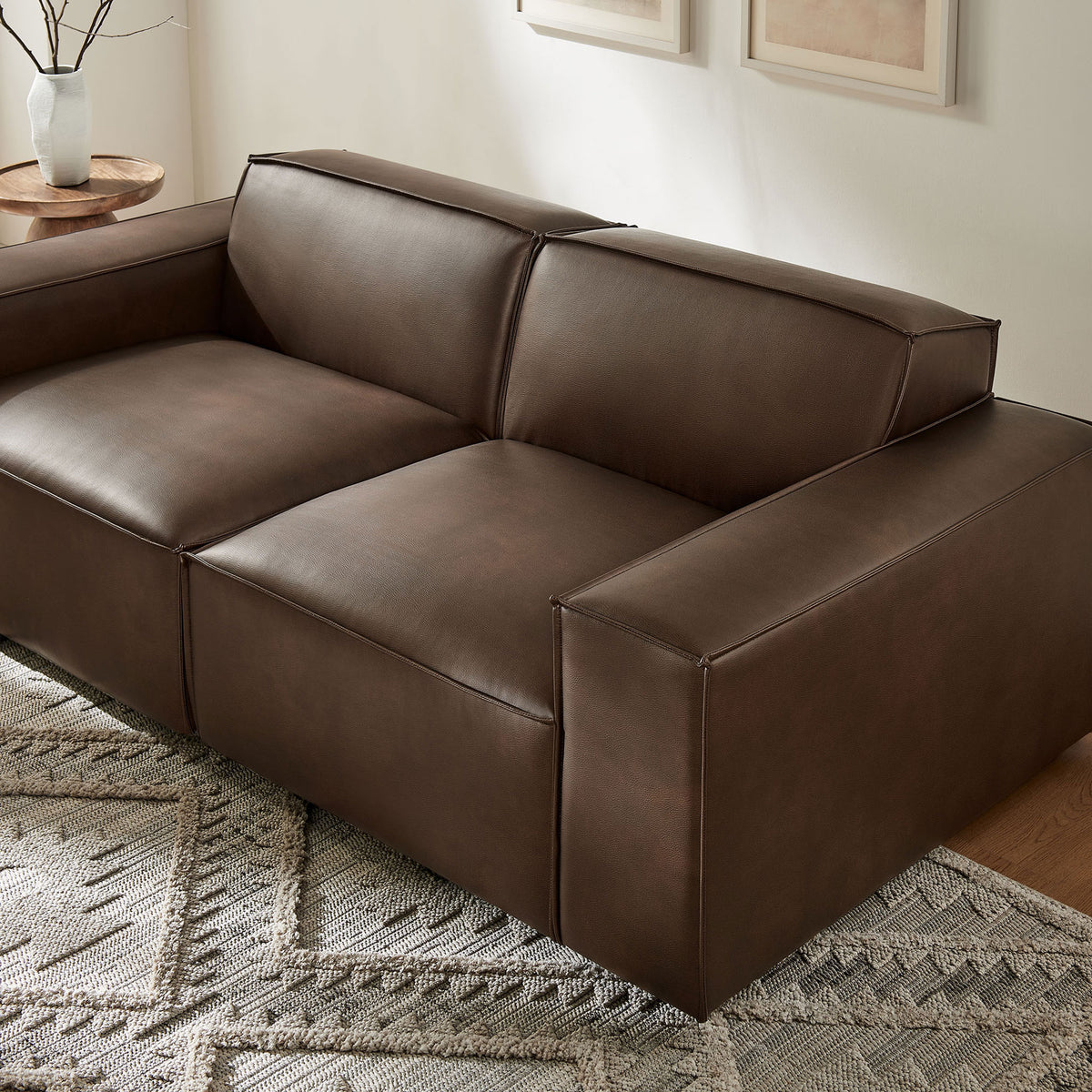 Espresso vegan leather modular loveseat styled with a textured rug and warm wood table. || EEI-7404-ESP || front_angle_room