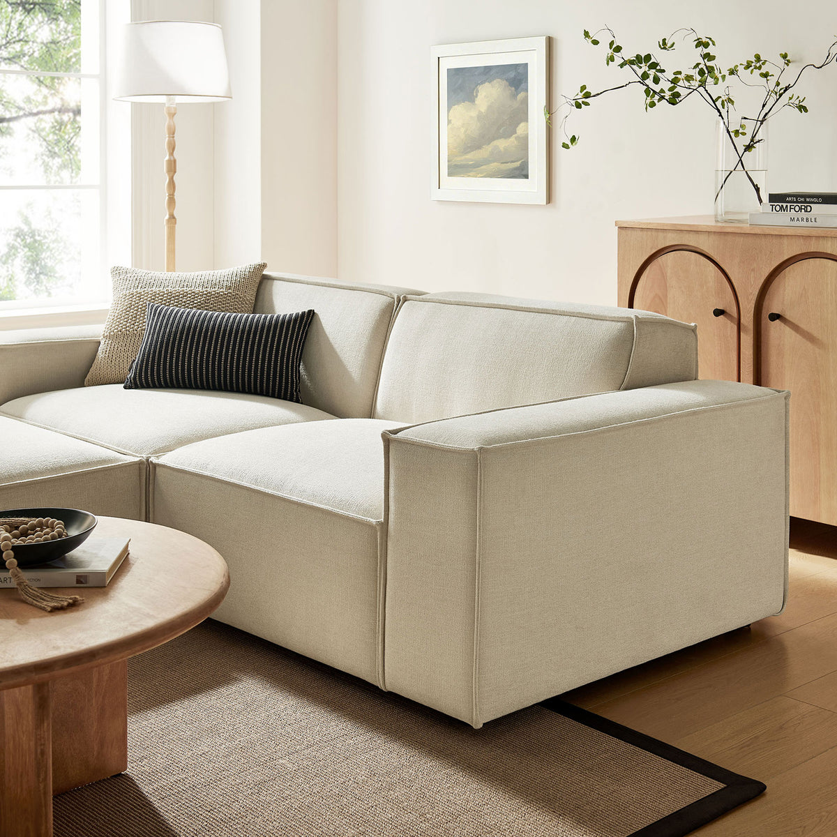 Restore ecru modular loveseat styled in a warm living room with modern wood accents. || EEI-7405-ECR || front_angle_partial_room