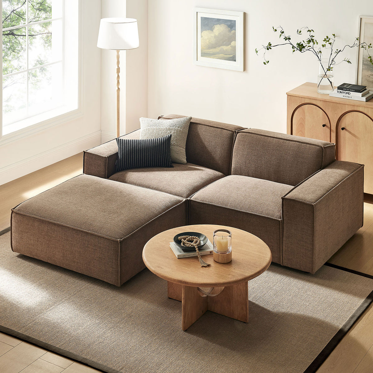 Spacious mocha loveseat with ottoman creates a cozy lounge area, paired with a modern coffee table and decor. || EEI-7405-MOC || front_angle_room