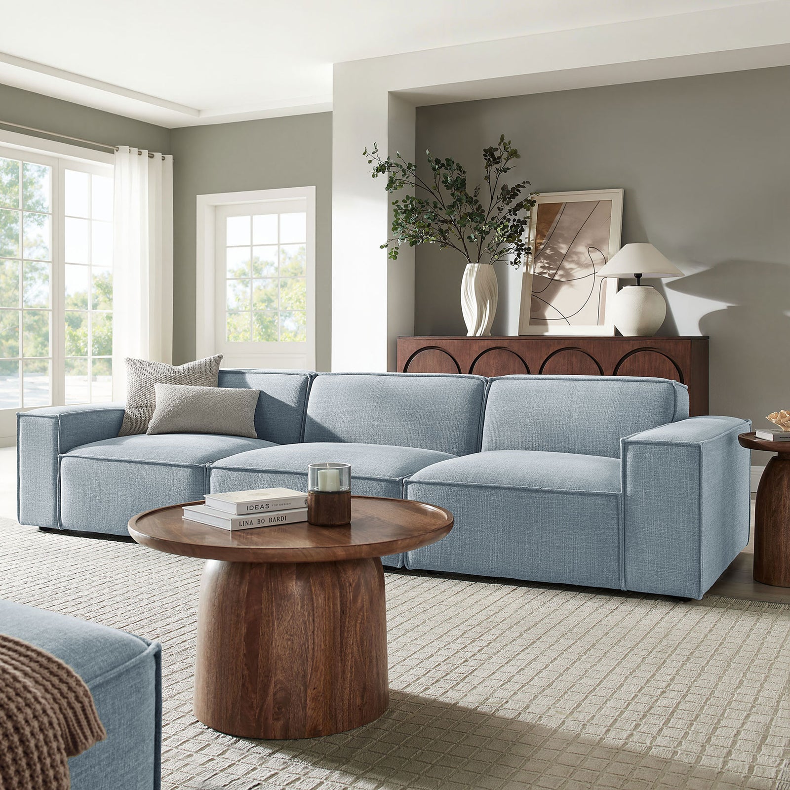 Sky blue three-piece modular sofa anchoring a bright living room with warm wood accents || EEI-7407-SKY || front_angle_room