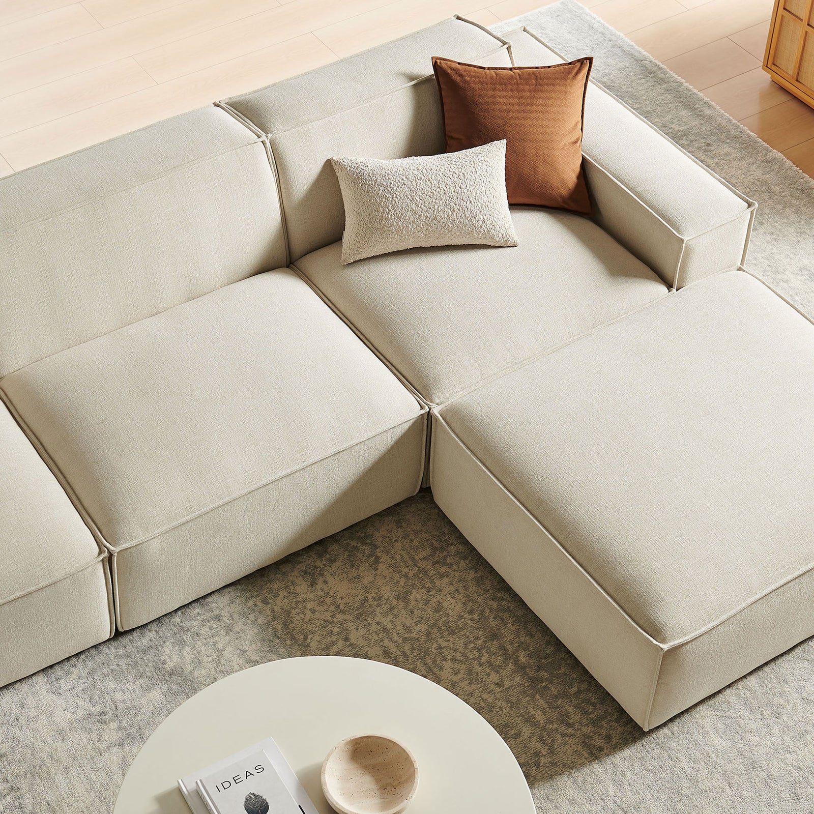 Textured ecru cushions styled with accent pillows on the modular sofa for cozy lounging || EEI-7409-ECR || detail_room