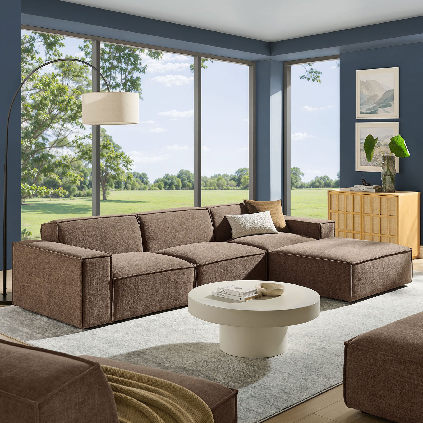 Full mocha sectional sofa with ottoman anchored in a modern living room with airy windows and layered decor. || EEI-7409-MOC || front_angle_room