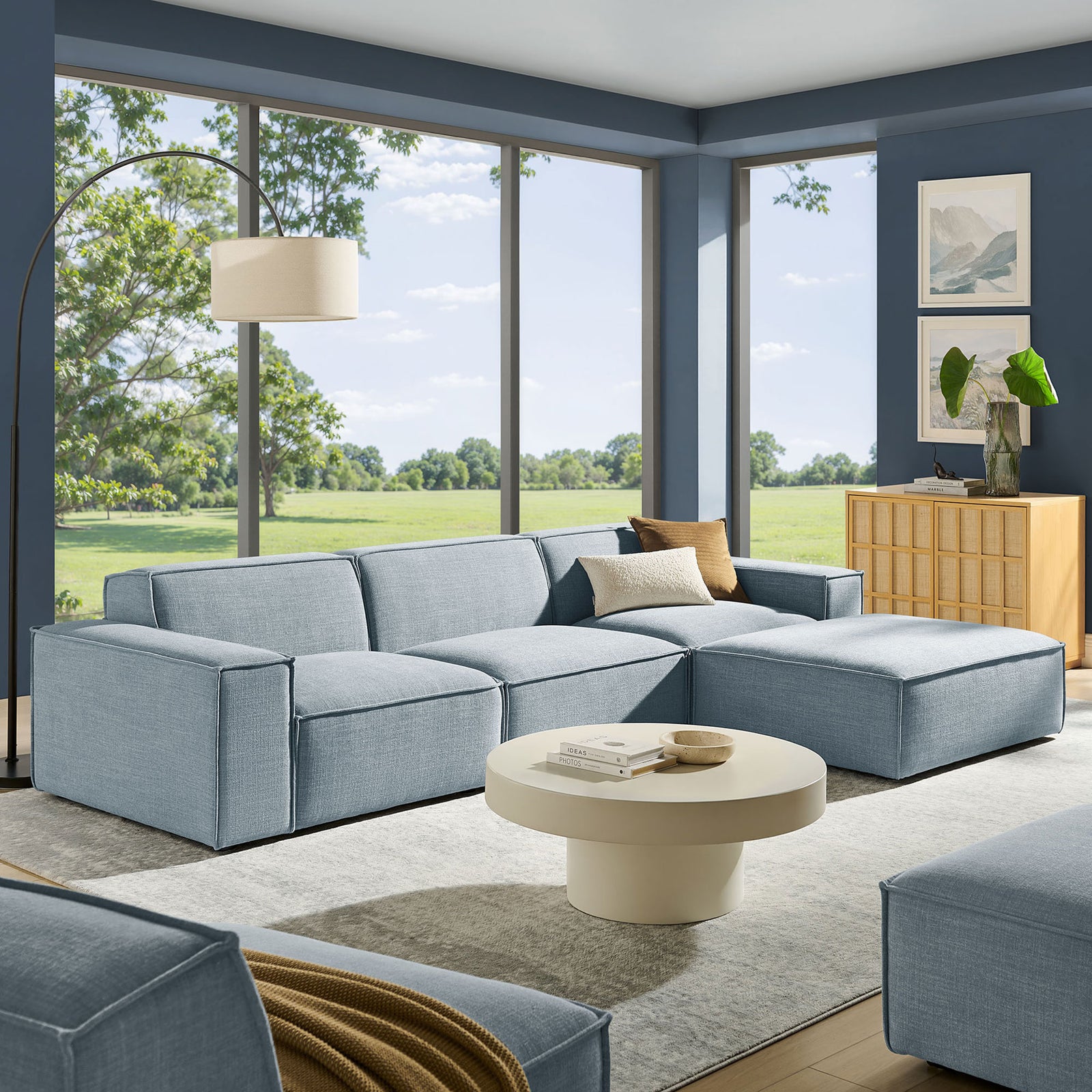 Spacious modular sectional with ottoman arranged in a contemporary living room for open, family-friendly lounging || EEI-7409-SKY || front_angle_room