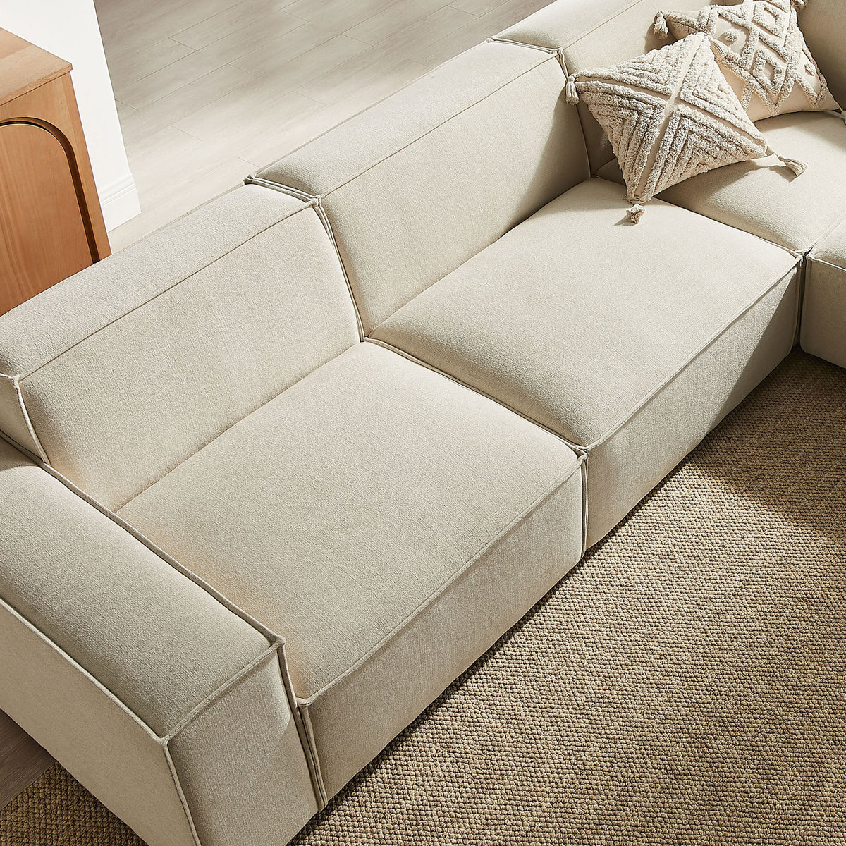 Section of the modular sofa styled with accent pillows on a neutral woven rug || EEI-7411-ECR || detail_room