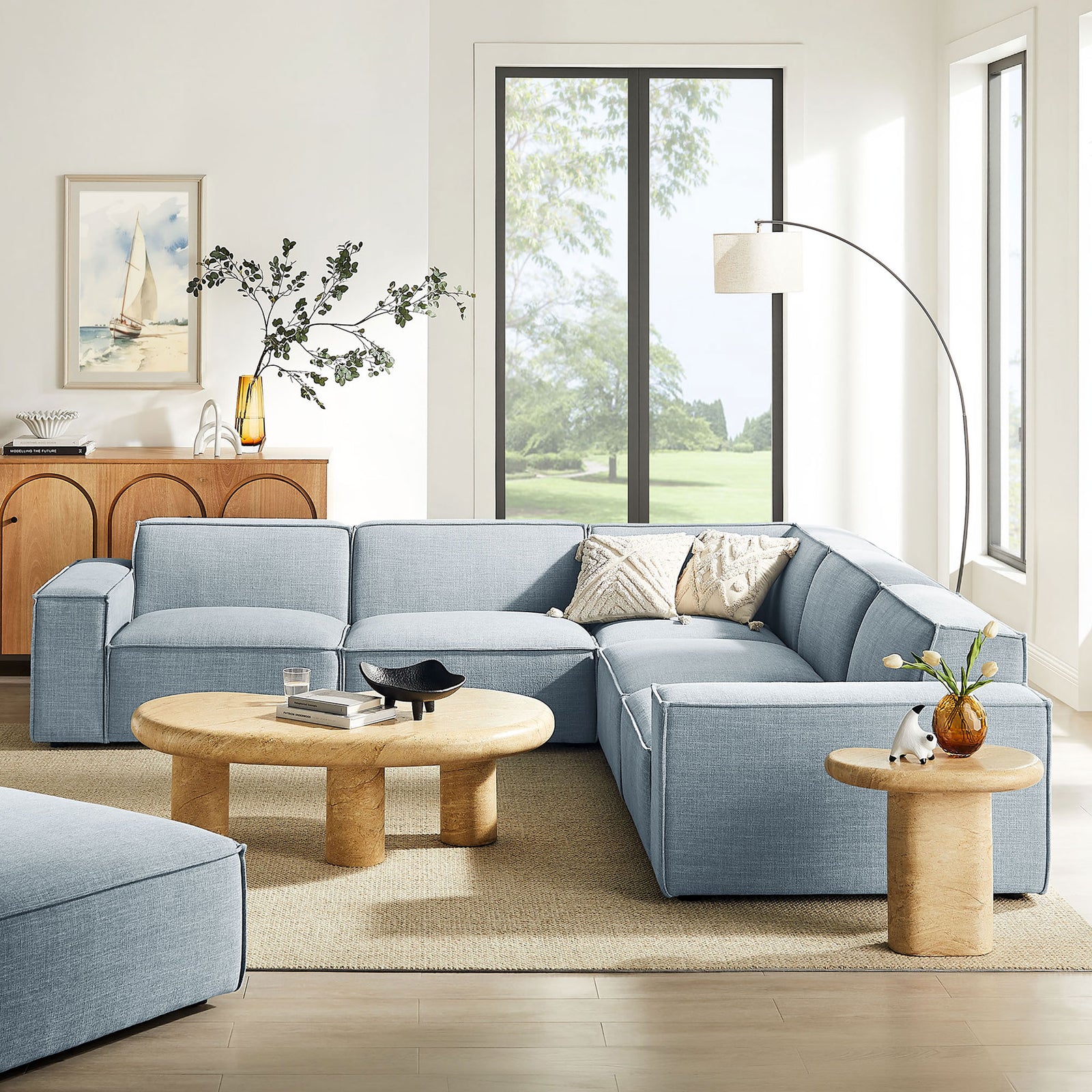 Airy living room featuring the sky blue modular sectional paired with light wood tables and a floor lamp || EEI-7411-SKY || front_angle_room