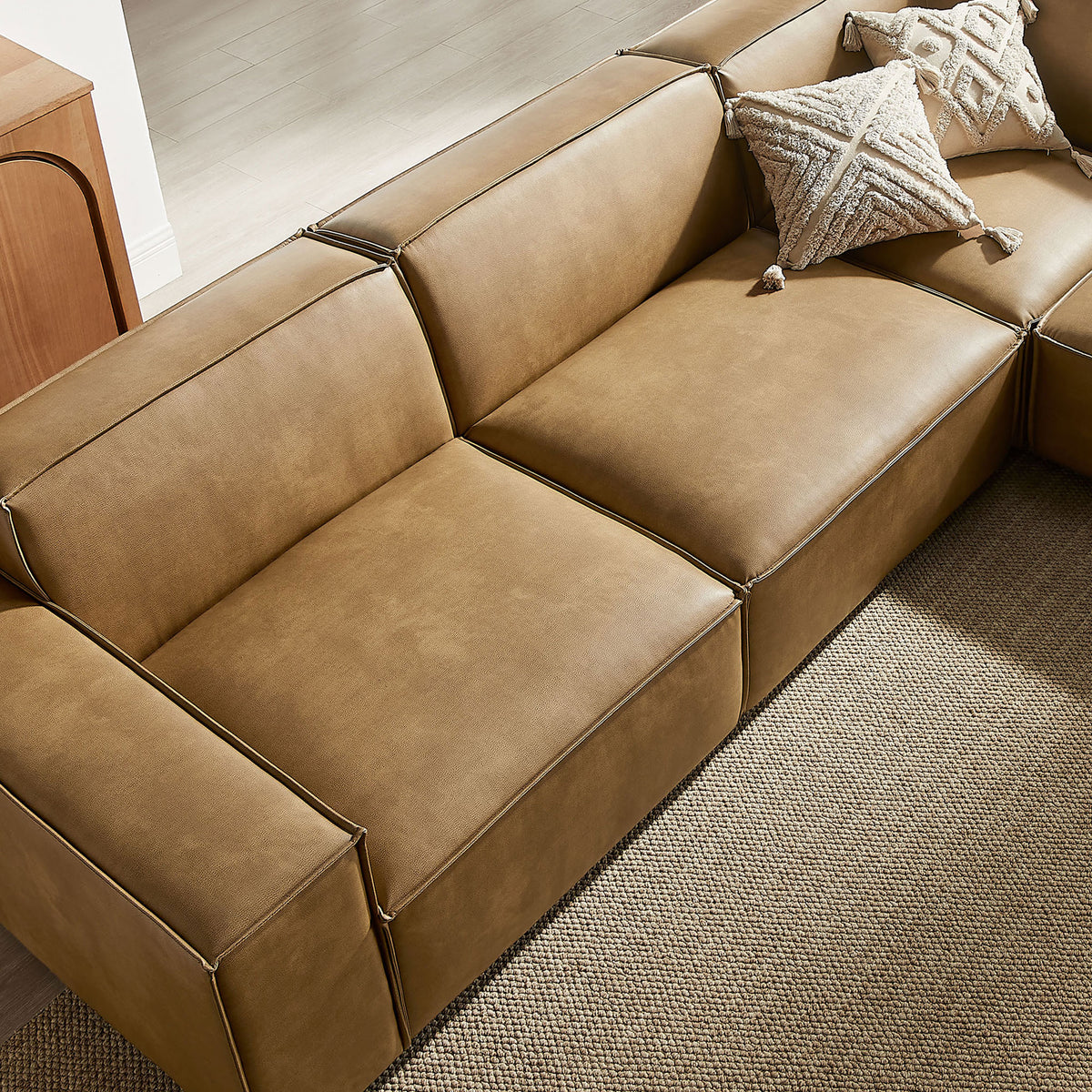 Sectional sofa seat in toast vegan leather styled with textured throw pillows on a neutral rug || EEI-7412-TST || detail_room