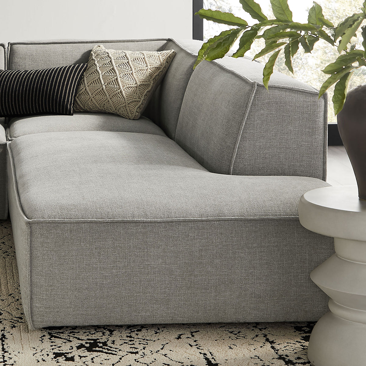 Corner of pewter modular sectional styled with textured accent pillows for cozy lounge seating || EEI-7413-PEW || detail_room