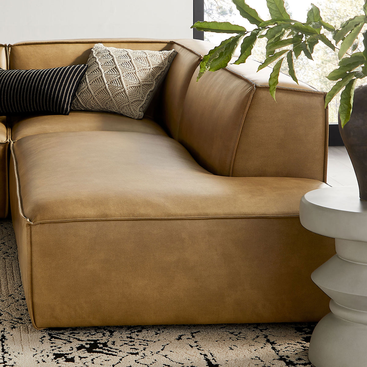 Curved corner of the toast sectional styled with textured accent pillows for inviting comfort. || EEI-7414-TST || detail_room
