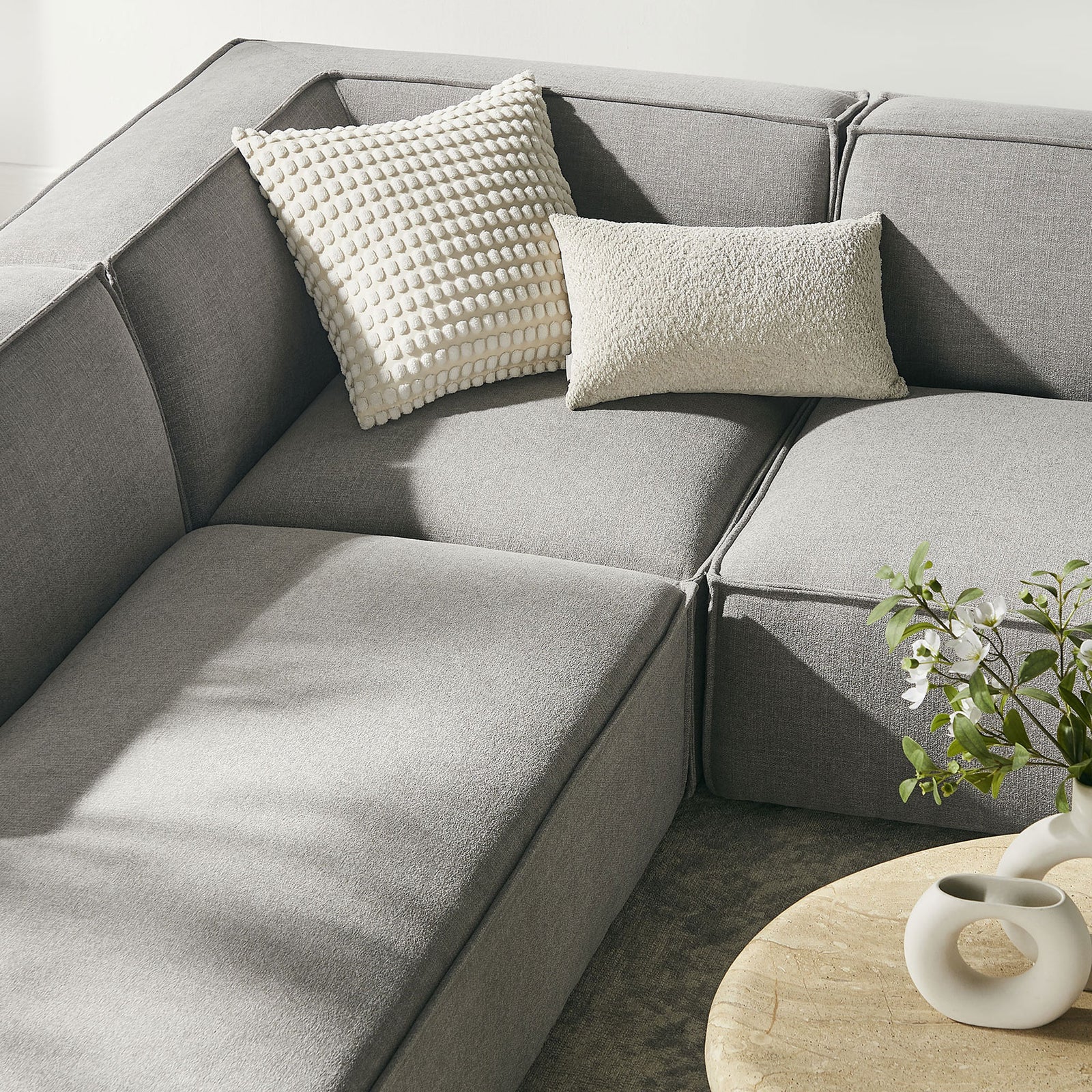 Cozy corner of pewter modular sectional styled with textured accent pillows and rounded coffee table || EEI-7415-PEW || detail_room