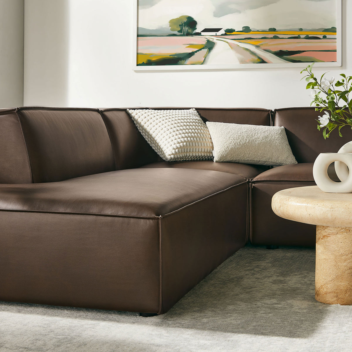 Espresso sectional seating anchors a modern living area with cozy pillows, artwork, and a sculptural table || EEI-7416-ESP || detail_room
