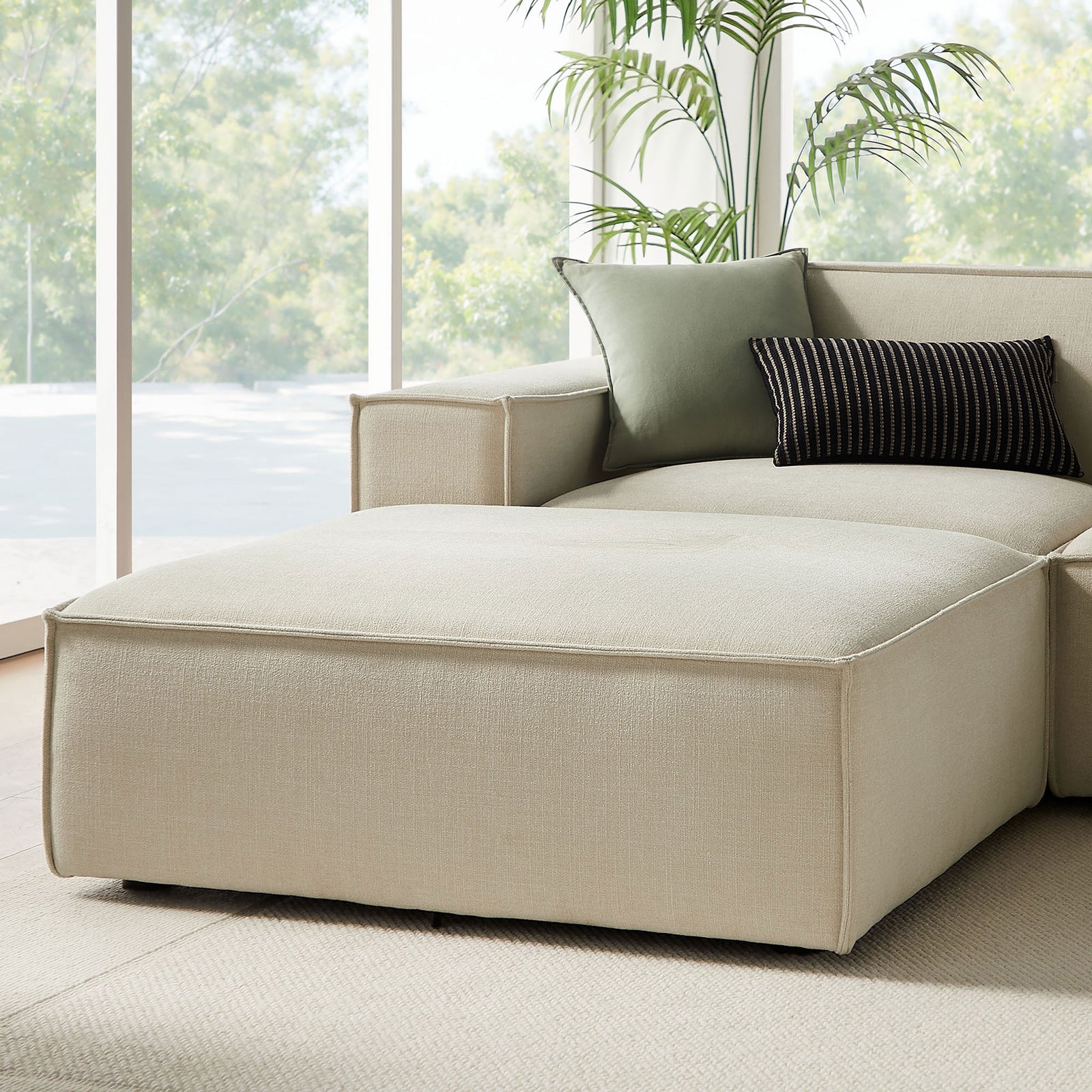 Detail of the chaise-style ottoman and corner seat with accent pillows on the ecru modular sectional || EEI-7417-ECR || detail_room