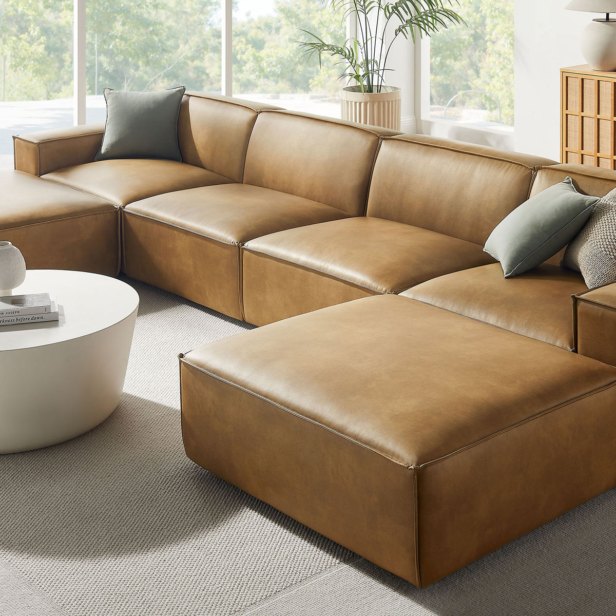 Restore vegan leather sectional styled with layered accent pillows and soft neutral rug in a sunlit corner. || EEI-7418-TST || detail_room