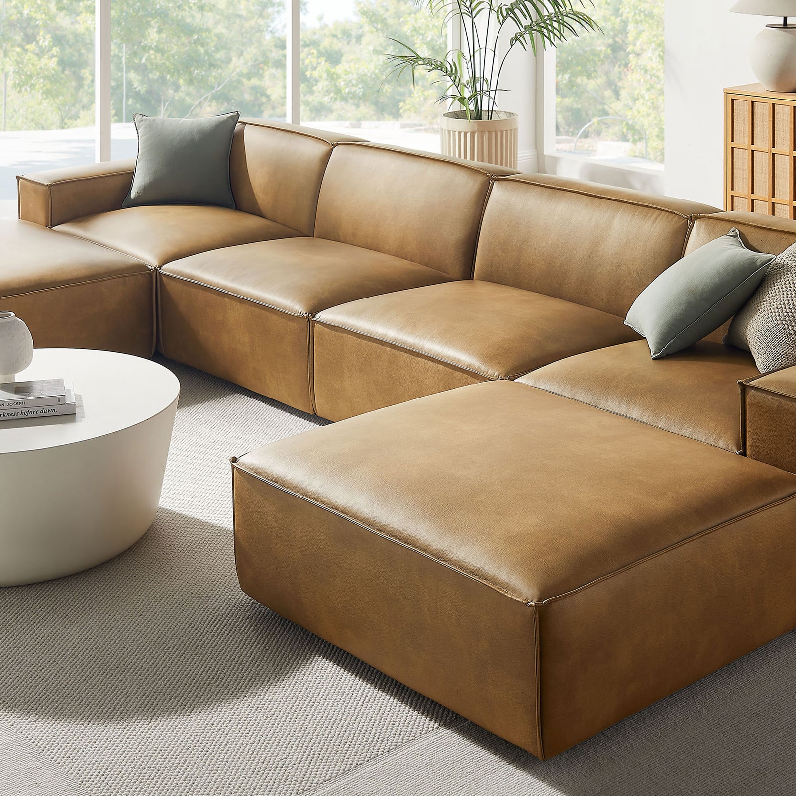 Restore vegan leather sectional styled with layered accent pillows and soft neutral rug in a sunlit corner. || EEI-7418-TST || detail_room