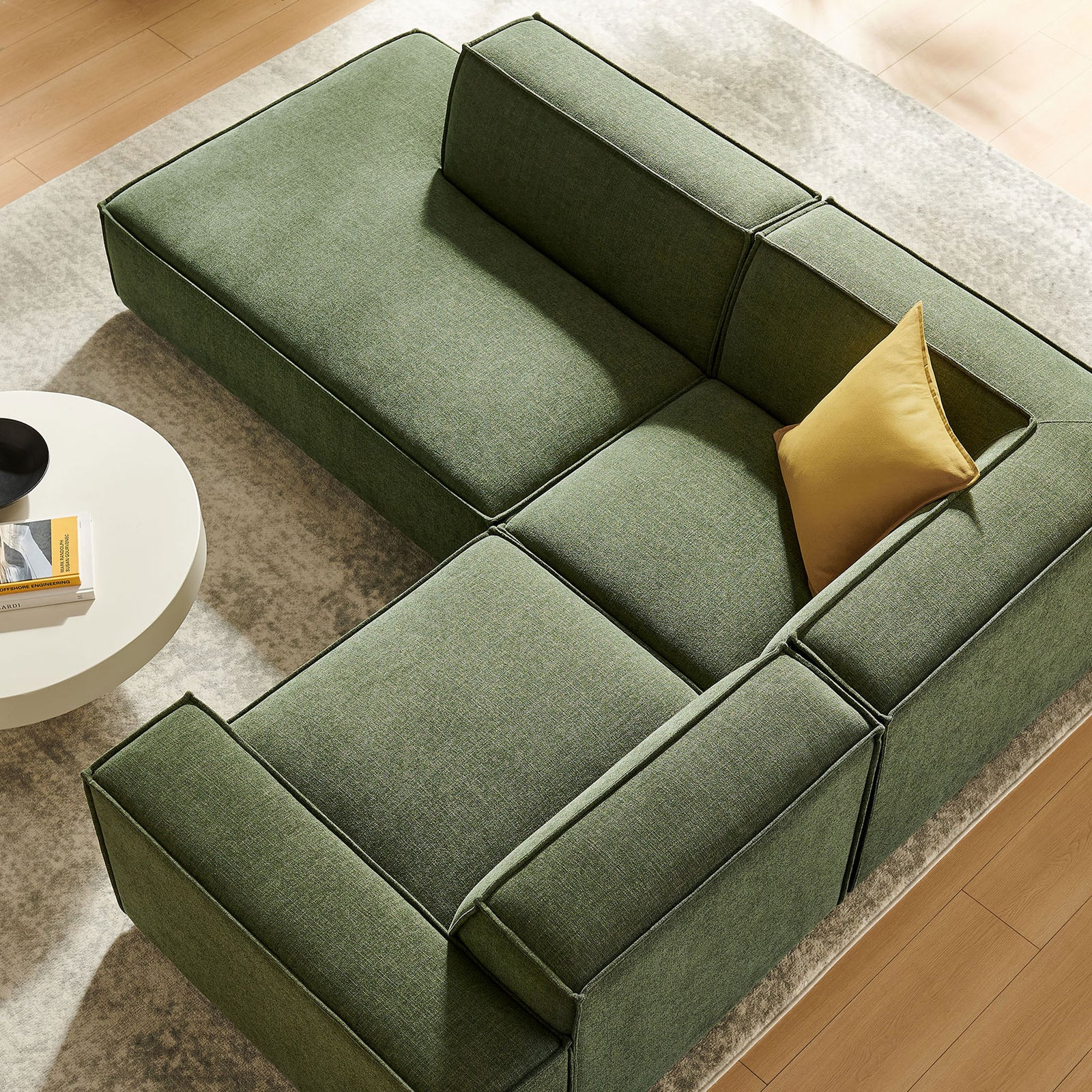Generous corner cushions and tailored seams on the green modular sectional arranged over a plush area rug || EEI-7419-FOL || detail_room