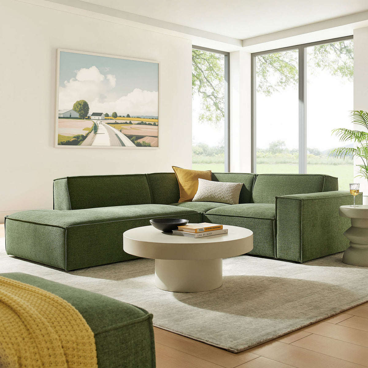 Green modular sectional with chaise arranged in a contemporary living room with round coffee table and artwork || EEI-7419-FOL || front_angle_room