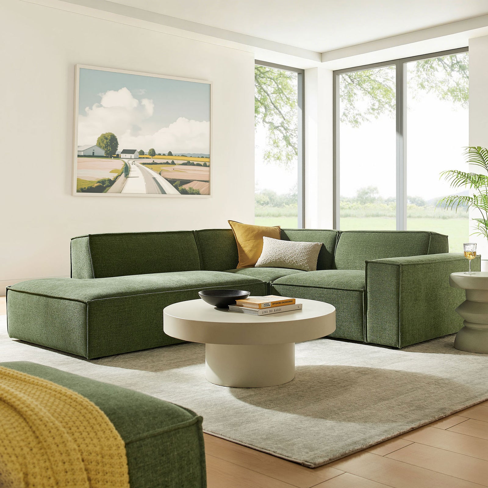 Green modular sectional with chaise arranged in a contemporary living room with round coffee table and artwork || EEI-7419-FOL || front_angle_room